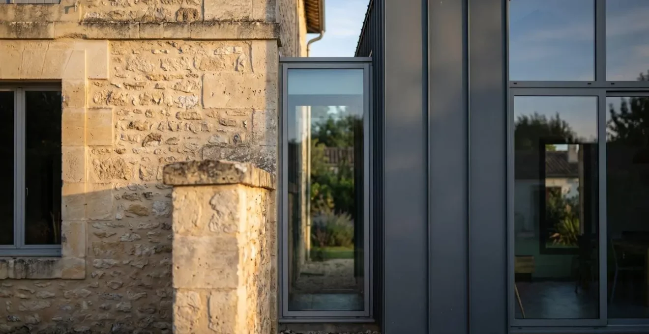 Jonction architecturale harmonieuse entre une façade traditionnelle française et une extension contemporaine vitrée, détail de la transition esthétique